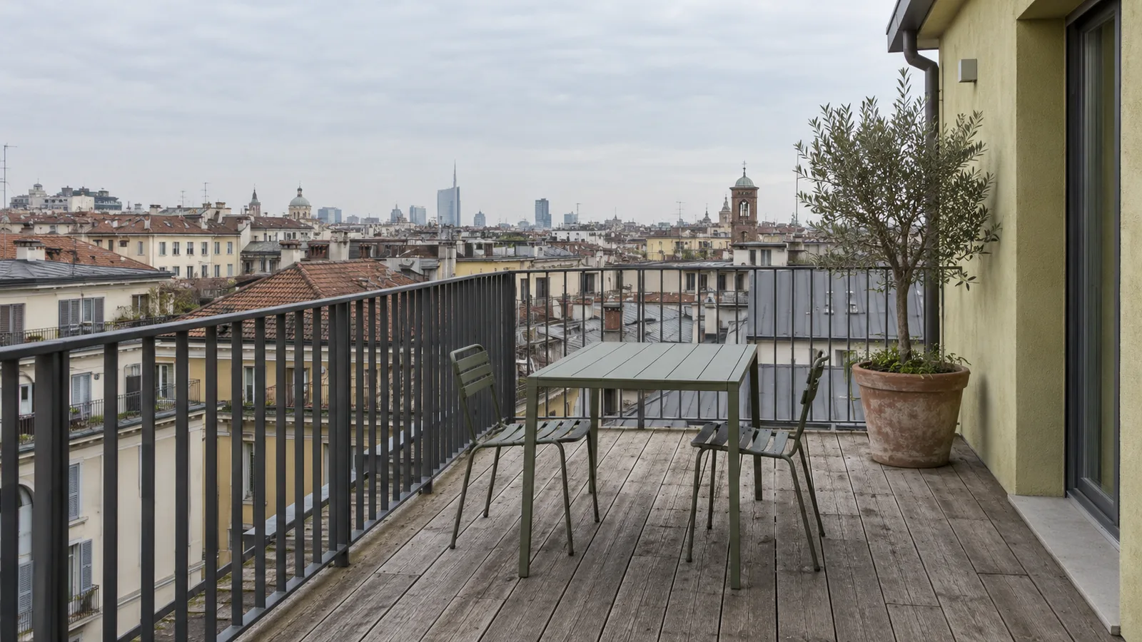 Terrazza di un attico a Milano con pavimento in legno, parapetto in ferro e vista sui tetti
