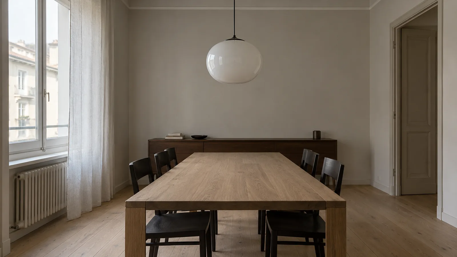 Sala da pranzo di un appartamento milanese anni Cinquanta con tavolo in frassino e pareti grigio chiaro